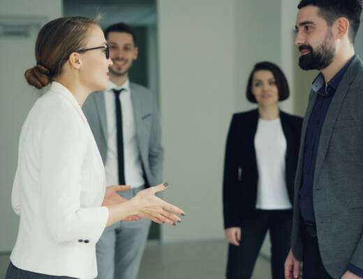 Two business people conversing, others observing; build business relationships