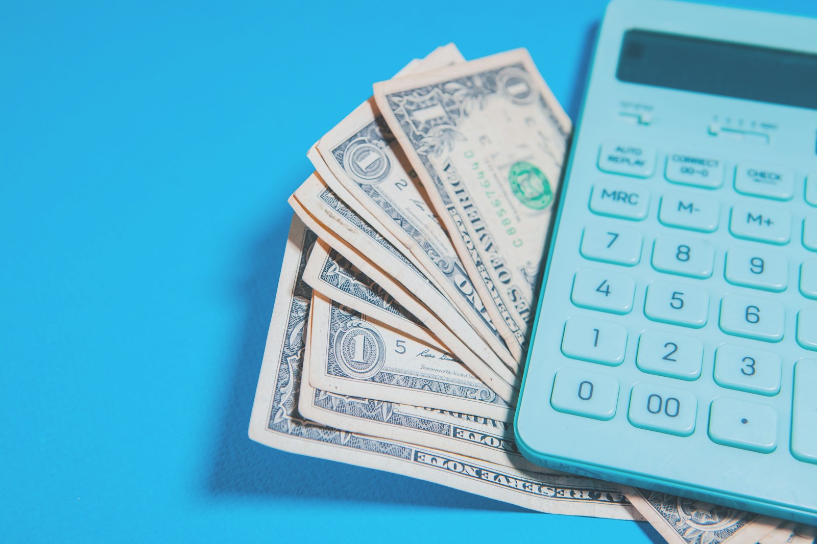 US dollar bills and a calculator on blue background; marriage requires shared money