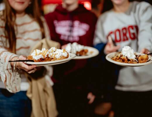 A group of people holding plates of funnel cake in focus; thriving funnel cake brand