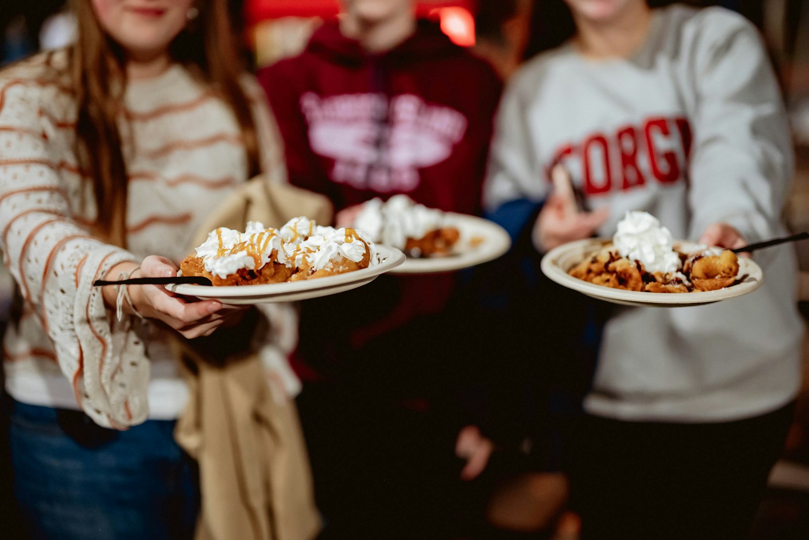 A group of people holding plates of funnel cake in focus; thriving funnel cake brand