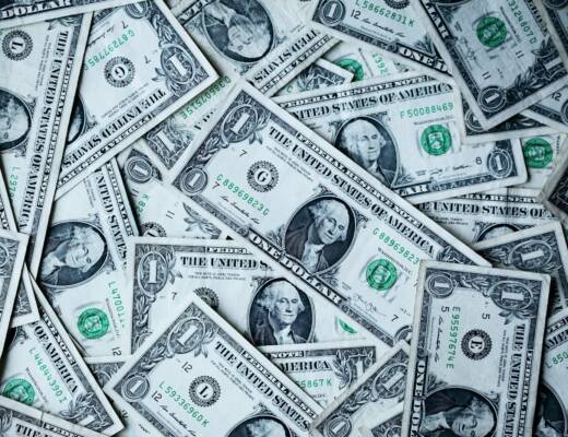 Close-up image of dollar bills laying flat on table; founders early money habits