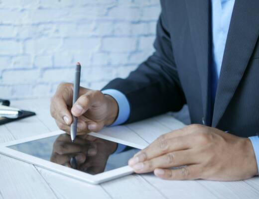 a man in a suit writing on a tablet; alternative education model