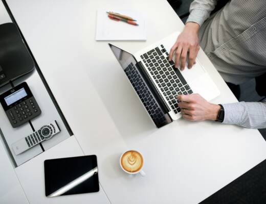 Person working at desk with coffee sitting beside laptop; competitive enterprises innovation