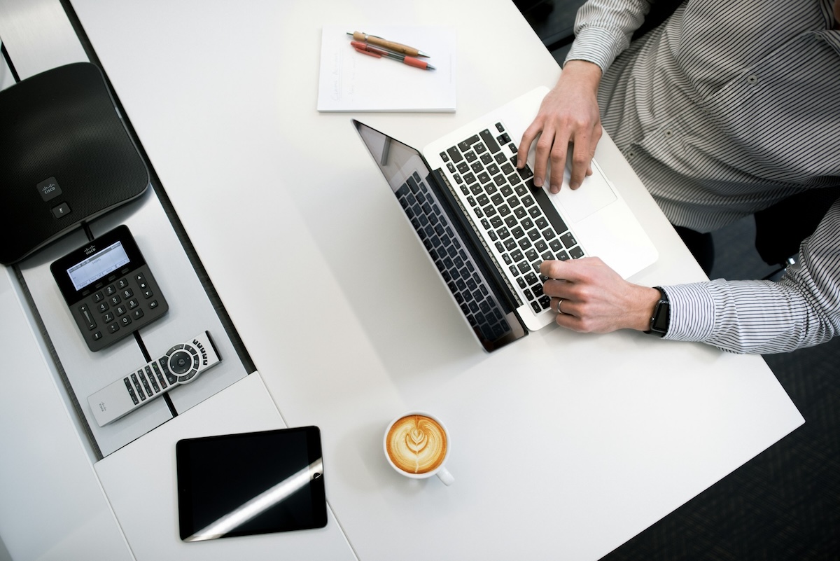 Person working at desk with coffee sitting beside laptop; competitive enterprises innovation