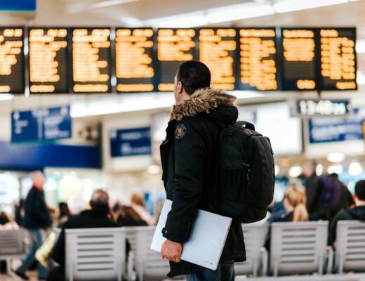man standing inside airport looking at LED flight schedule bulletin board; choose travel data plan
