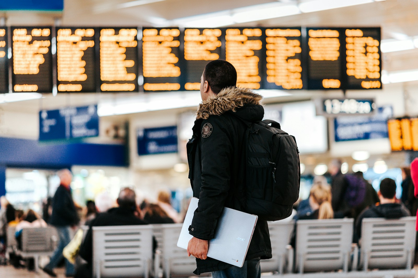 man standing inside airport looking at LED flight schedule bulletin board; choose travel data plan