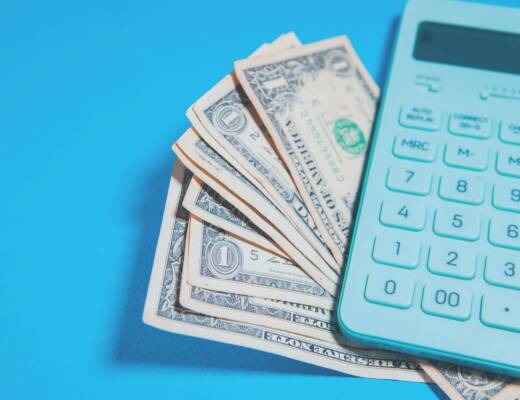 Calculator and cash sitting on blue tabletop; debt relief promises