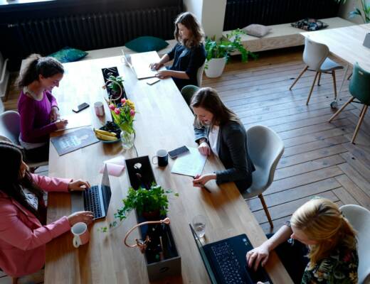 a group of people sitting around a wooden table; founders break rules