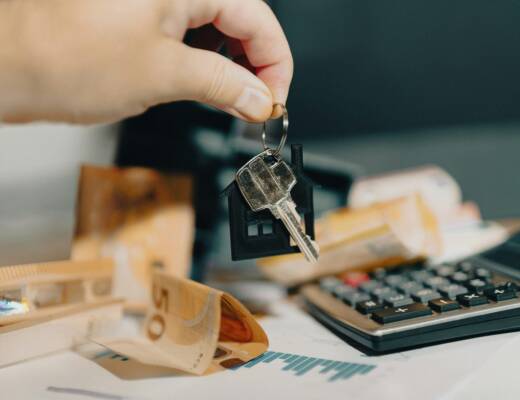 A person holding a house key in front of a calculator; landlord heroics fund retirement