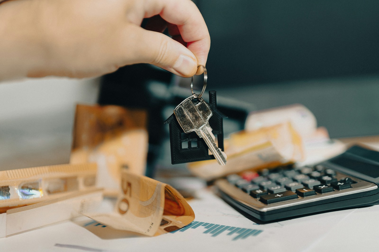 A person holding a house key in front of a calculator; landlord heroics fund retirement